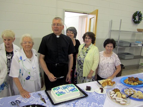 Father Michael does the ceremonial cutting of the cake